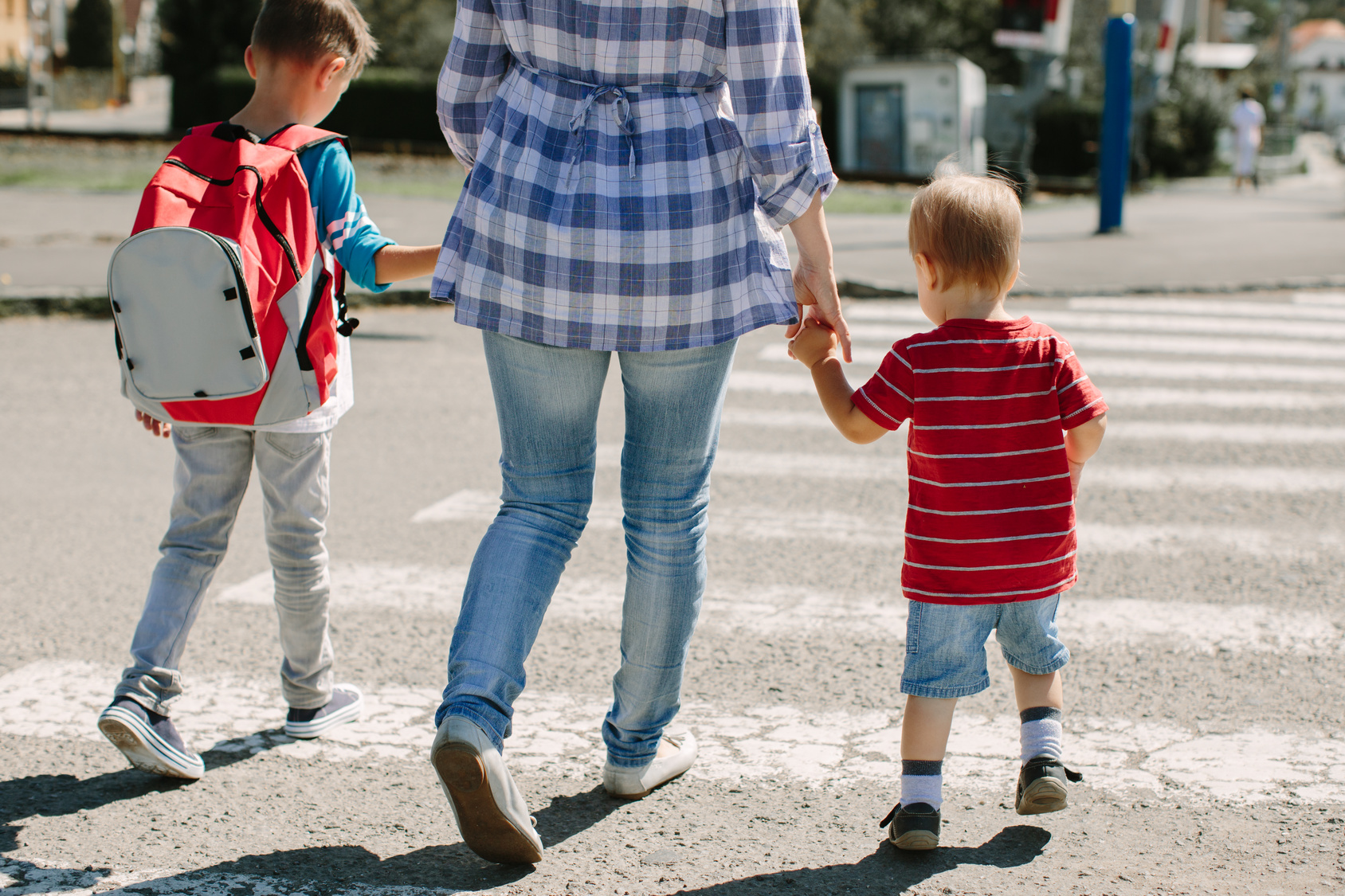 Adult holding children's hands crossing the road