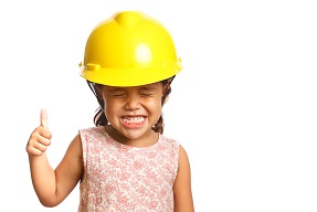 Young girl in hard hat giving thumbs up