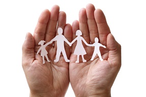 Pair of hands holding paper cut out of family group