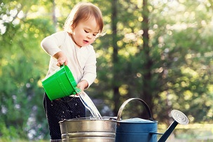 Child pouring water into a watering can