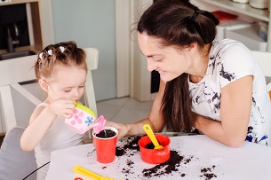 Adult watching a child watering a pot