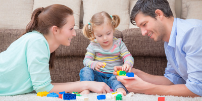 Man and woman lying on stomachs playing with a toddler girl