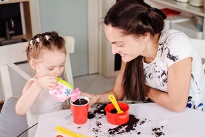 Adult watching child watering a pot