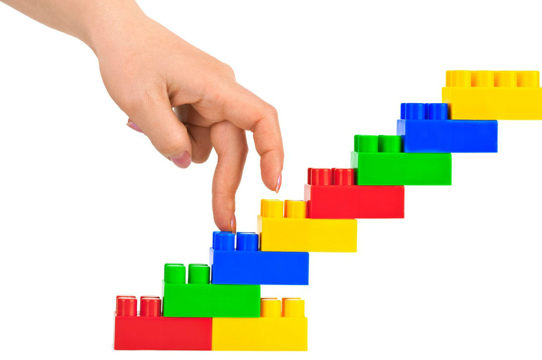 Fingers walking up plastic toy building blocks