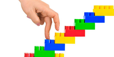 Fingers walking up plastic toy building blocks