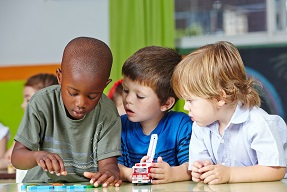Three boys playing with toy cars