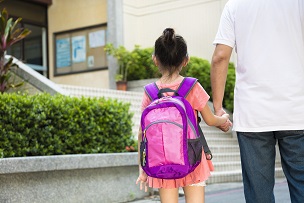 Child holding hands with adult going to school