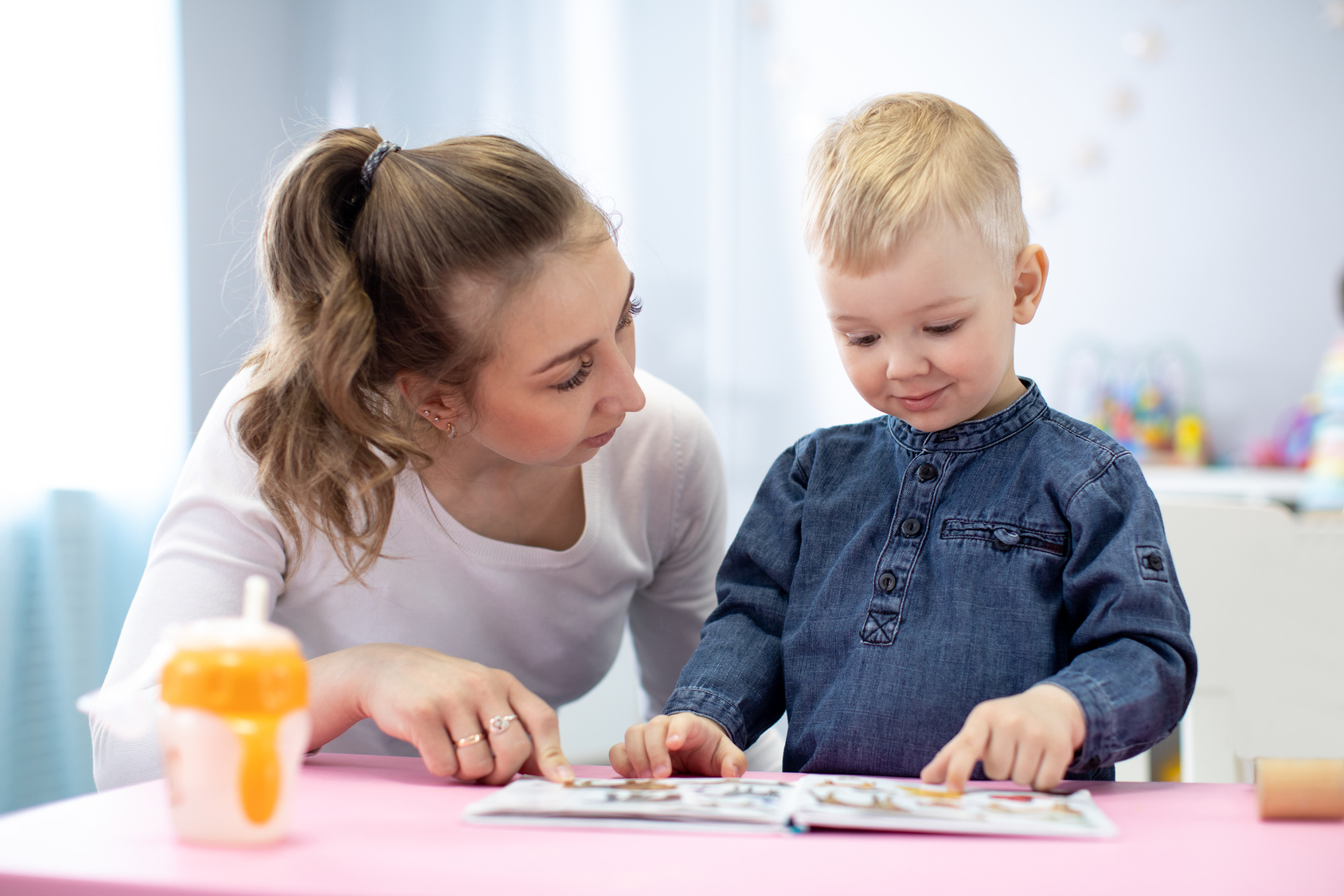Woman talking to a young boy and looking at a book