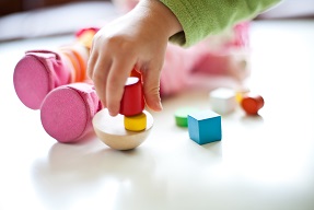 Hand using wooden bricks and shapes