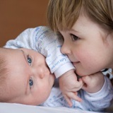 Young girl lying close to baby boy