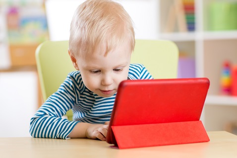 Toddler boy looking at a tablet in a red case