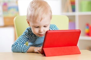 Toddler boy looking at a tablet in a red case