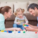 Man and woman lying on stomachs playing with a toddler girl