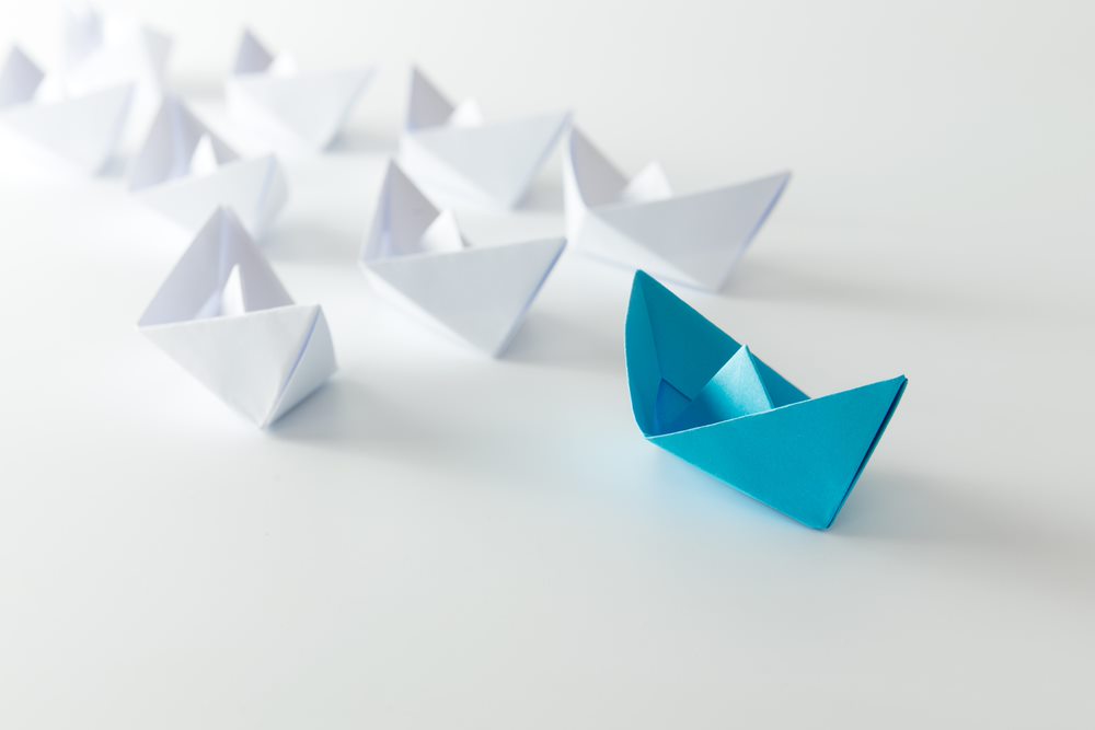 blue paper boat leading other boats