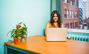 Woman smiling, sitting in front of a laptop