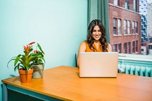 Woman smiling, sitting in front of a laptop