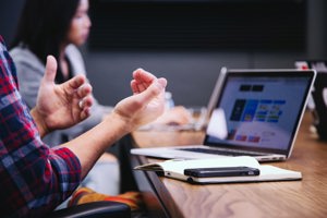 male hands gesturing near an open laptop