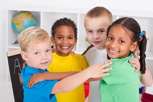 4 young ethnically diverse children smiling with arms around each other