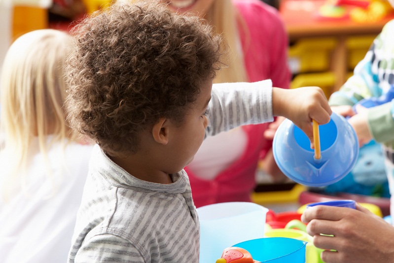 Young black boy in nursery setting with toy teapot