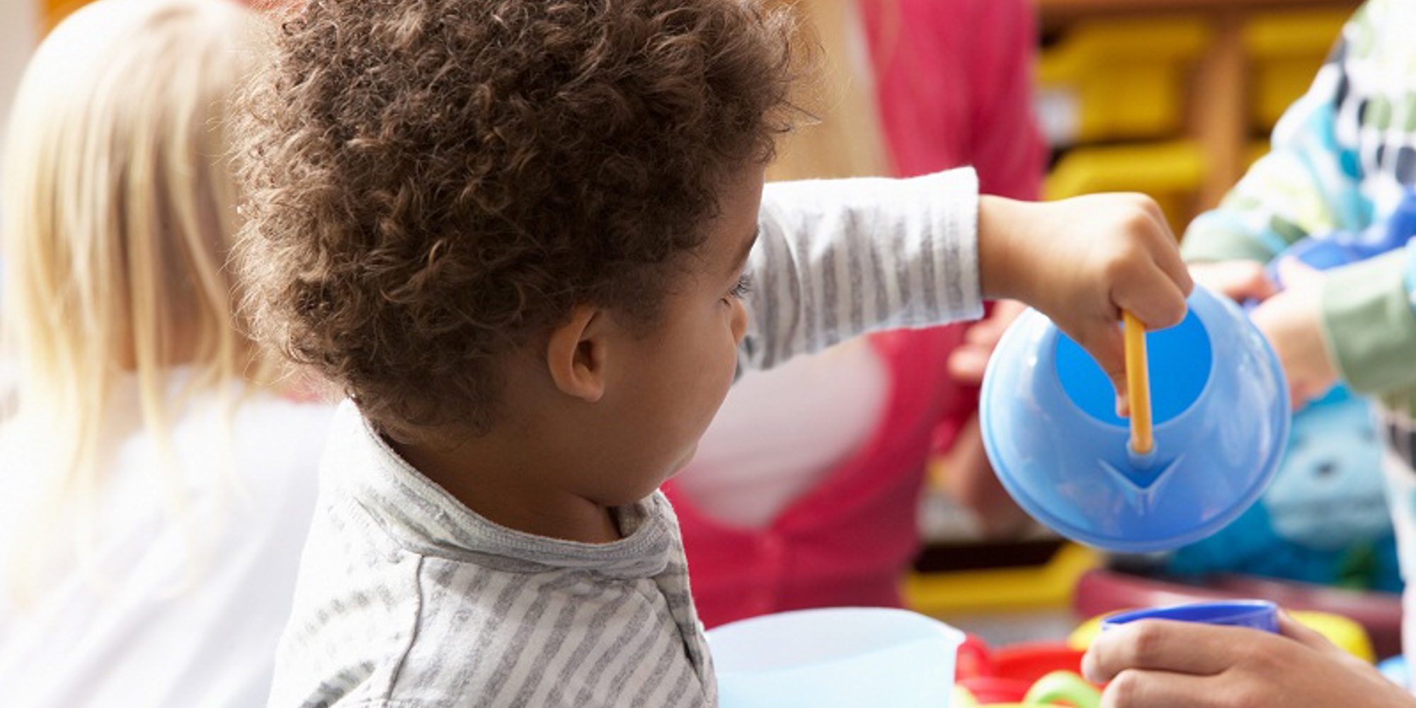 Young black boy in nursery setting with toy teapot
