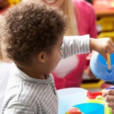 Young black boy in nursery setting with toy teapot
